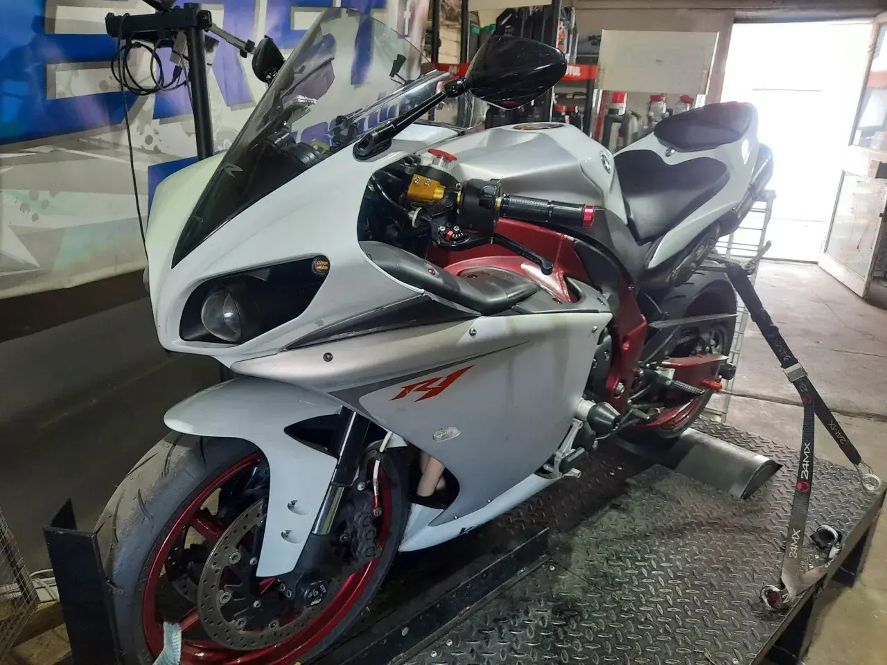 Biały motocykl sportowy na hamowni, przygotowany do **blokowania motocykla na A2**.