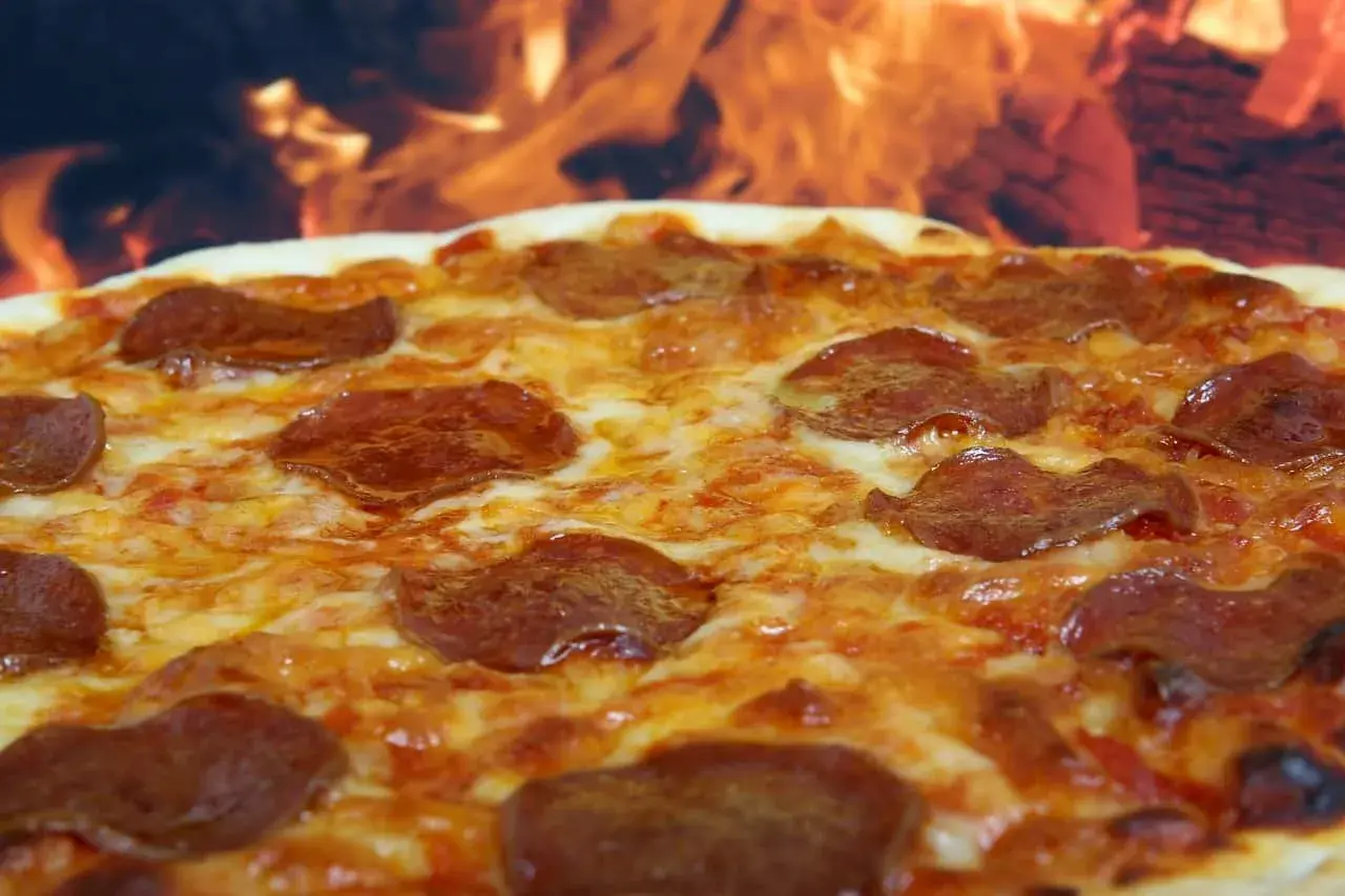 Pyszna pepperoni pizza z ciągnącym się serem, pieczona w ogniu.