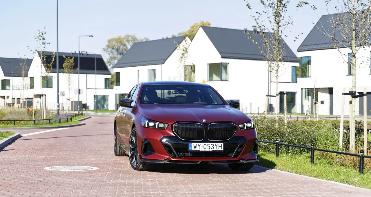 Czerwone bmw 550e na tle nowoczesnych domów.
