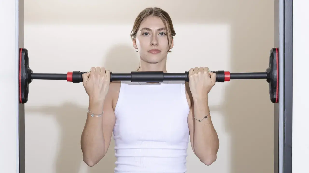 Frau hält Klimmzugstange Türrahmen Test. Einfache Montage für das Training zu Hause.