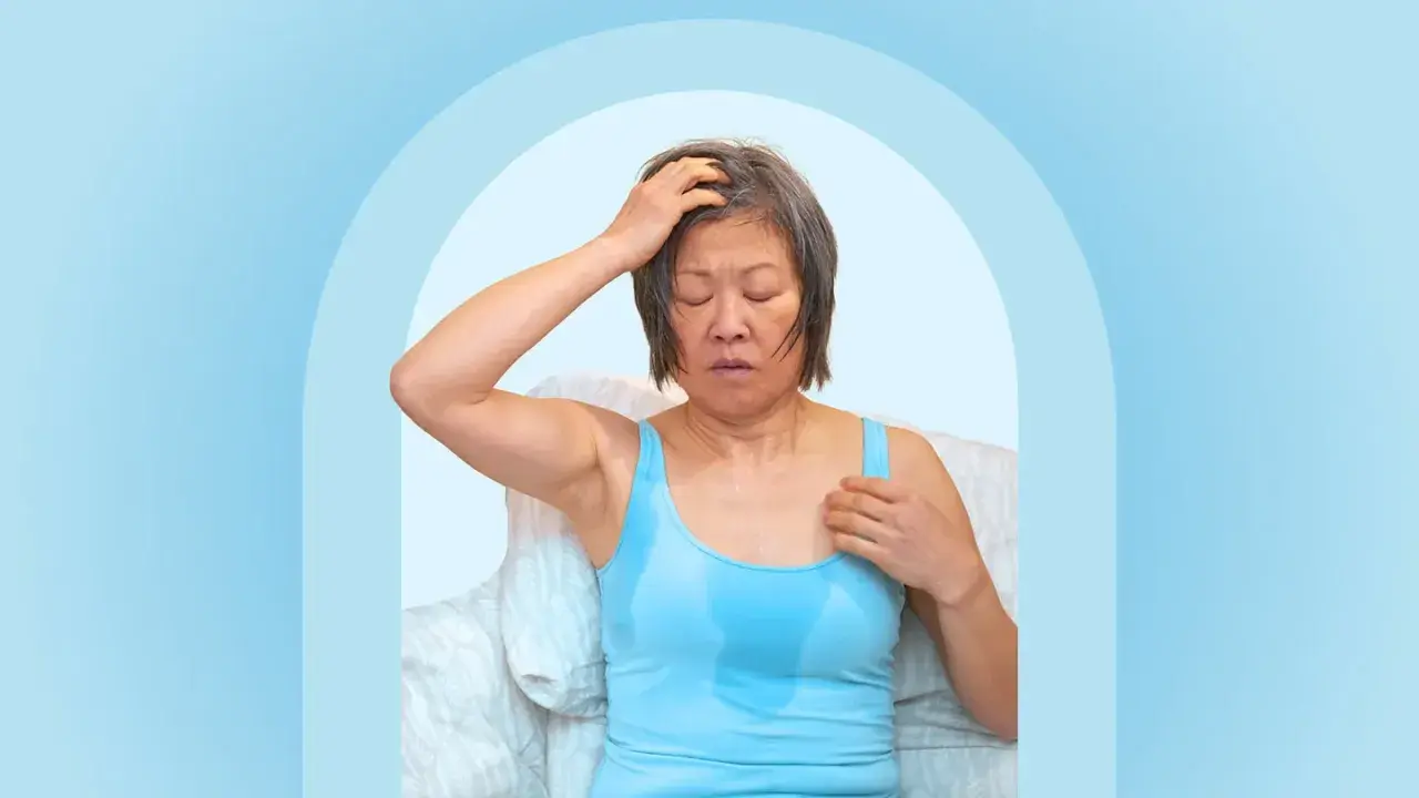 A woman experiencing night sweats after working out, with sweat visible on her tank top and forehead.