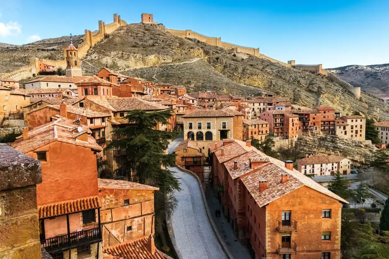 Pueblo medieval con casas de terracota y murallas en la ladera. Merece la pena visitar Teruel por su encanto histórico y vistas espectaculares.