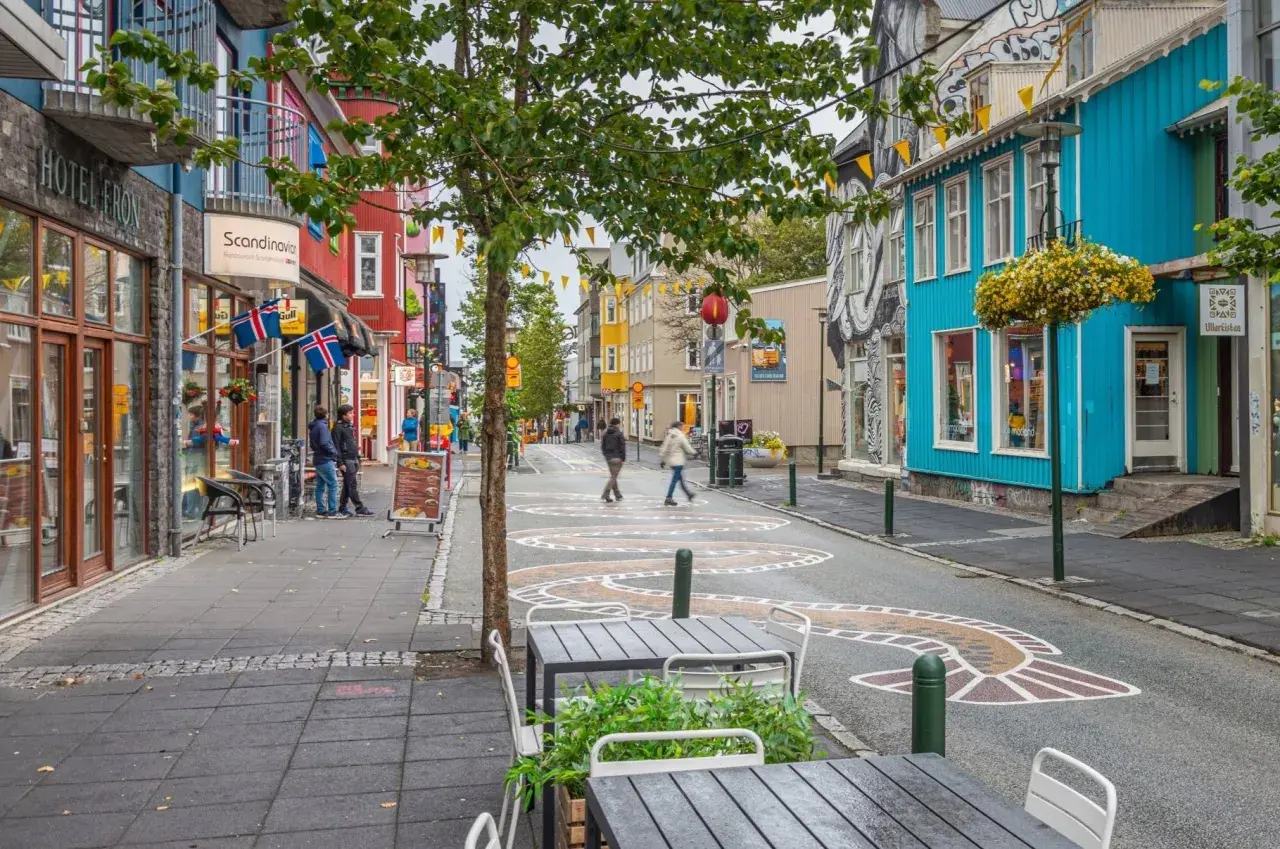 Kolorowa ulica w Reykjaviku z budynkami, flagami Islandii i artystycznymi wzorami na jezdni.