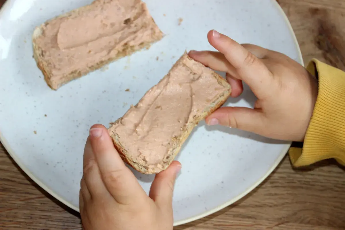 Kind hält Brot mit Leberwurst. Ab wann Leberwurst Baby? Erste Kostprobe für den Nachwuchs.