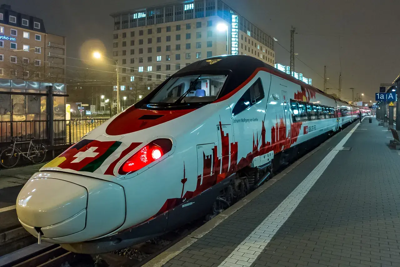 Moderner EC train in Deutschland mit Schweizer Flagge und Skyline-Design.