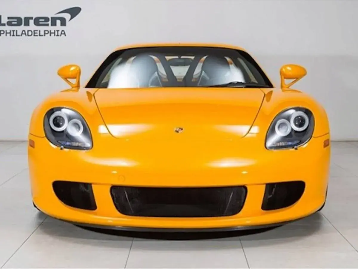 Pomarańczowy Porsche Carrera GT z charakterystycznymi okrągłymi światłami i sportowym grillem.