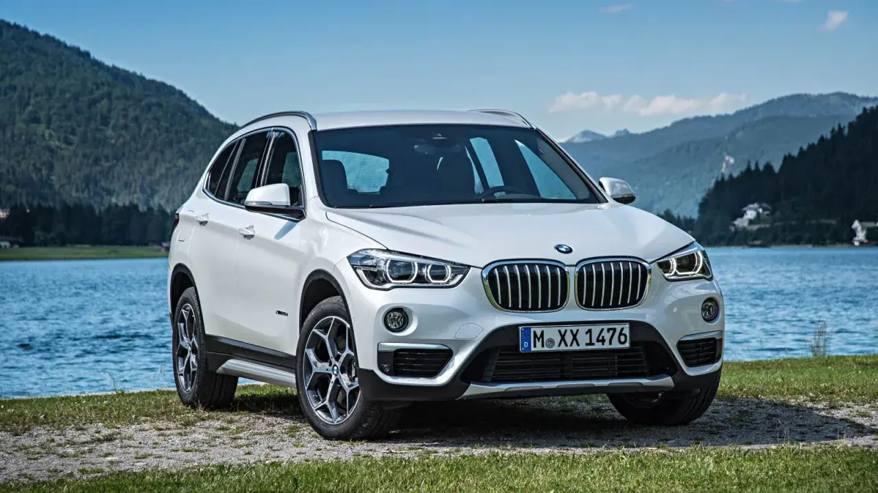 BMW X1 blanco aparcado junto a un lago. Opiniones sobre el mantenimiento de este modelo son positivas.