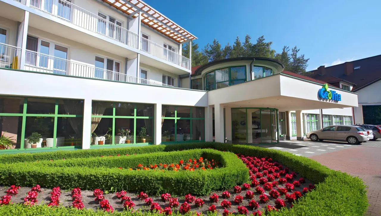 GeoVita Dąbki cennik: nowoczesny budynek hotelowy z zadbanym ogrodem i kwiatami.