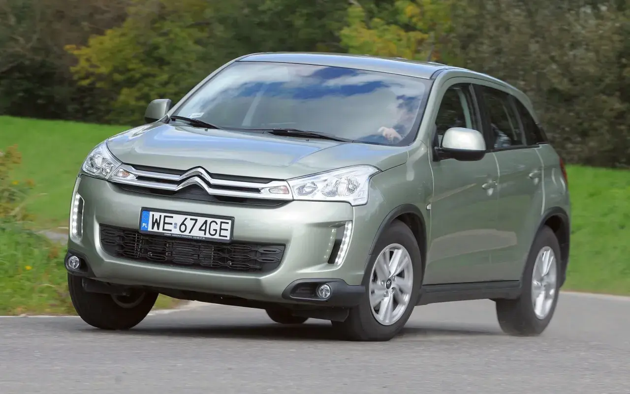 Zielony Citroen C4 Aircross z polskimi tablicami WE 674GE jedzie po drodze wśród zieleni.