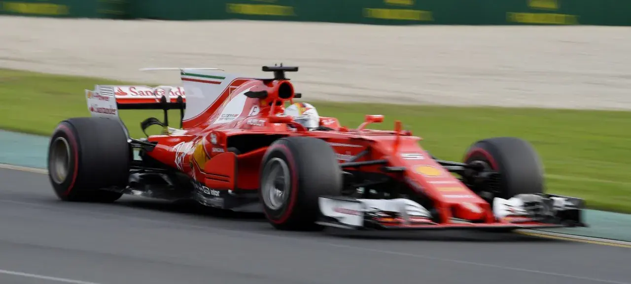 Ein roter Ferrari-Rennwagen rast über die Strecke, ein Meisterwerk der Formel 1 Technik, mit dem Fahrer im Cockpit.