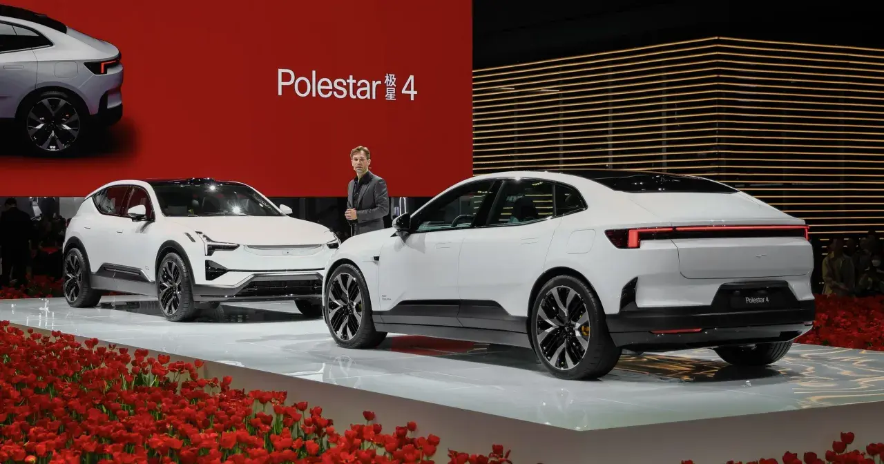 Dwa białe samochody Polestar 4 na scenie z czerwonym tłem i tulipanami.