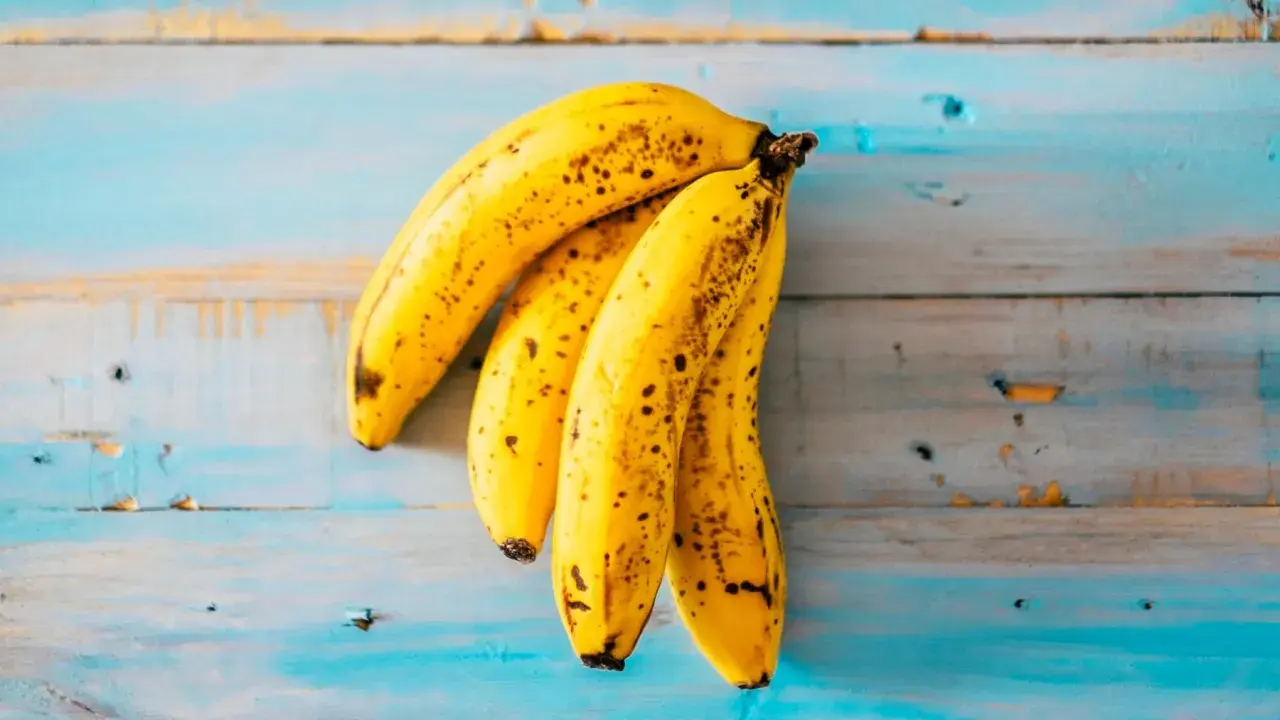 Un racimo de plátanos maduros sobre una superficie de madera azul desgastada. ¡Parece que alguien podría soñar con plátanos!