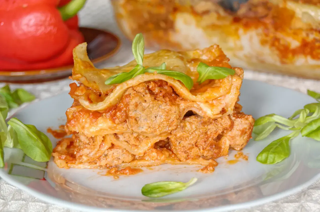 Pyszna porcja lasagne napoli z mięsem mielonym i sosem pomidorowym, udekorowana listkami bazylii.