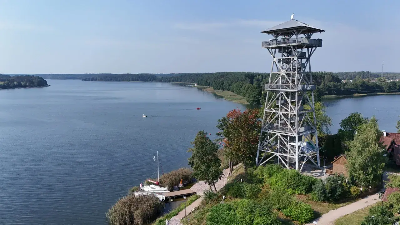 Wieża widokowa we Wdzydzach góruje nad jeziorem, oferując malowniczy widok na wodę i las.