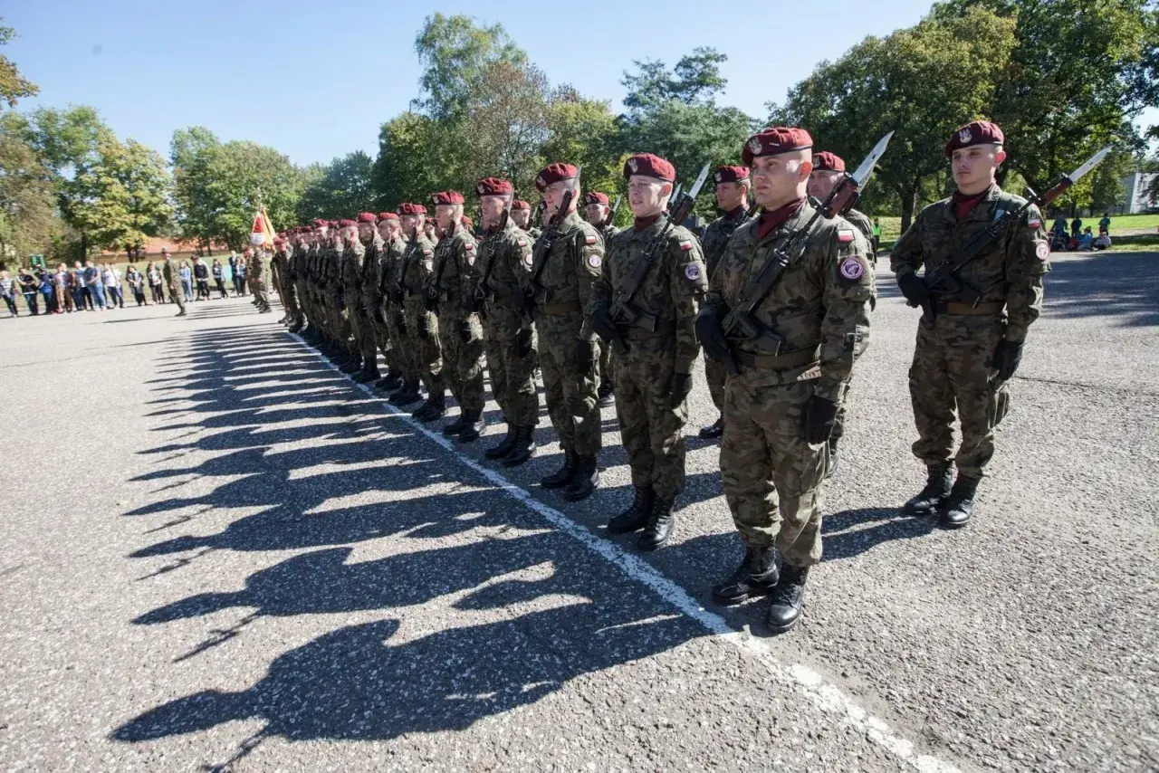 Chorąży w wojsku stoi na apelu w pełnym rynsztunku, gotowy do służby.