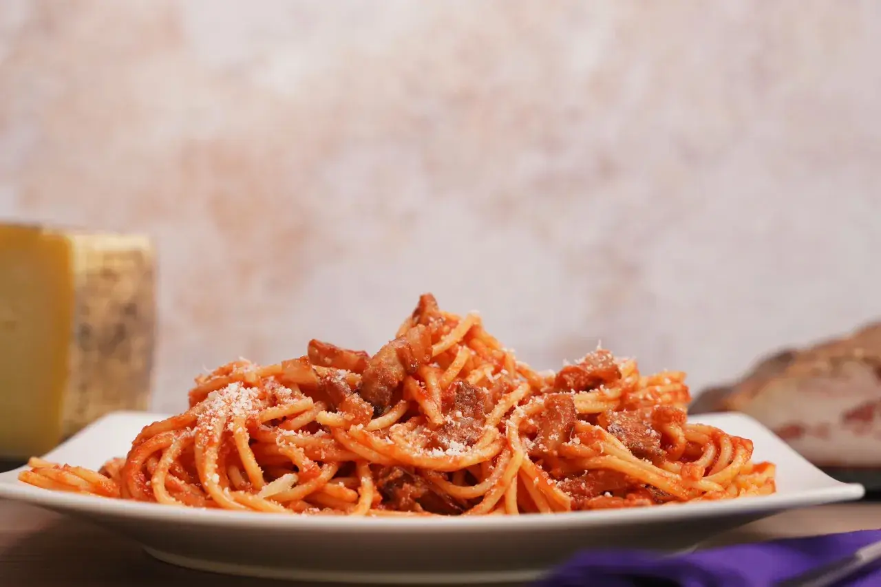 Un piatto di spaghetti conditi con sugo rosso e guanciale croccante, un assaggio dell'amatriciana ricetta originale di Amatrice.