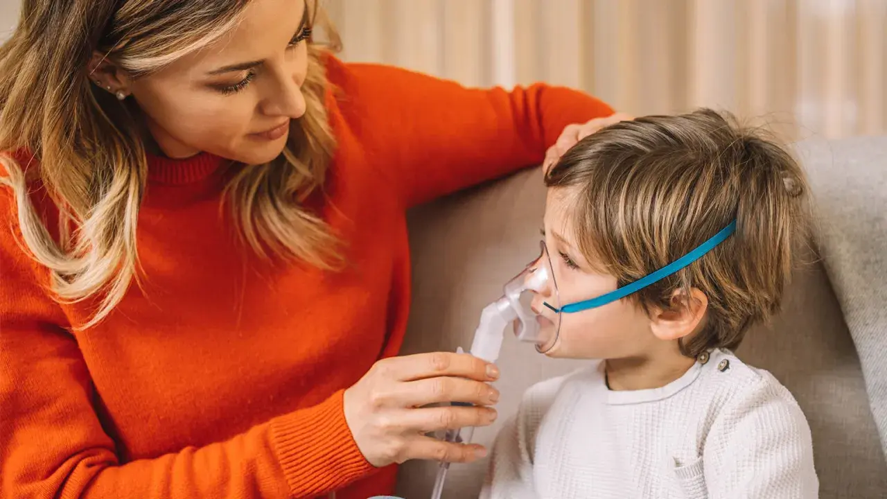 Mamma assiste il bambino con inalatore per il broncospasmo.