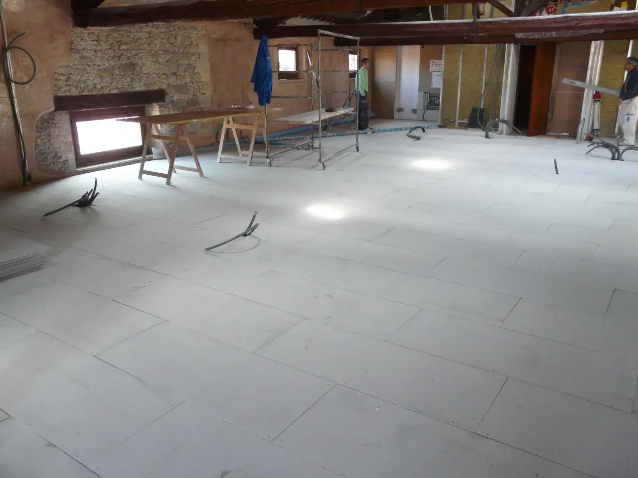 Pannelli per insonorizzare il pavimento in fase di posa, con tubi e attrezzature da cantiere.