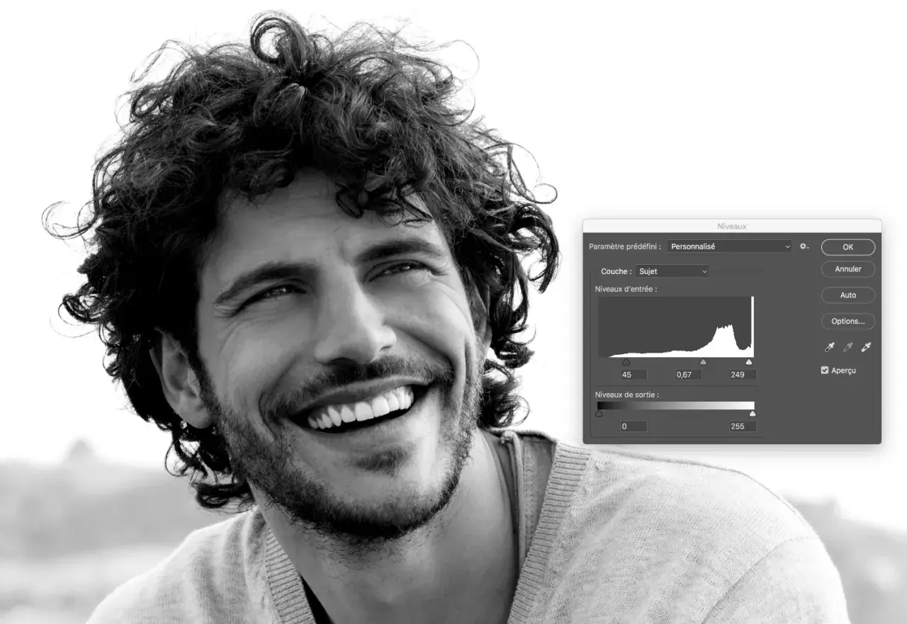 Portrait en noir et blanc d'un homme souriant, ajustant les niveaux dans Photoshop pour un rendu parfait.