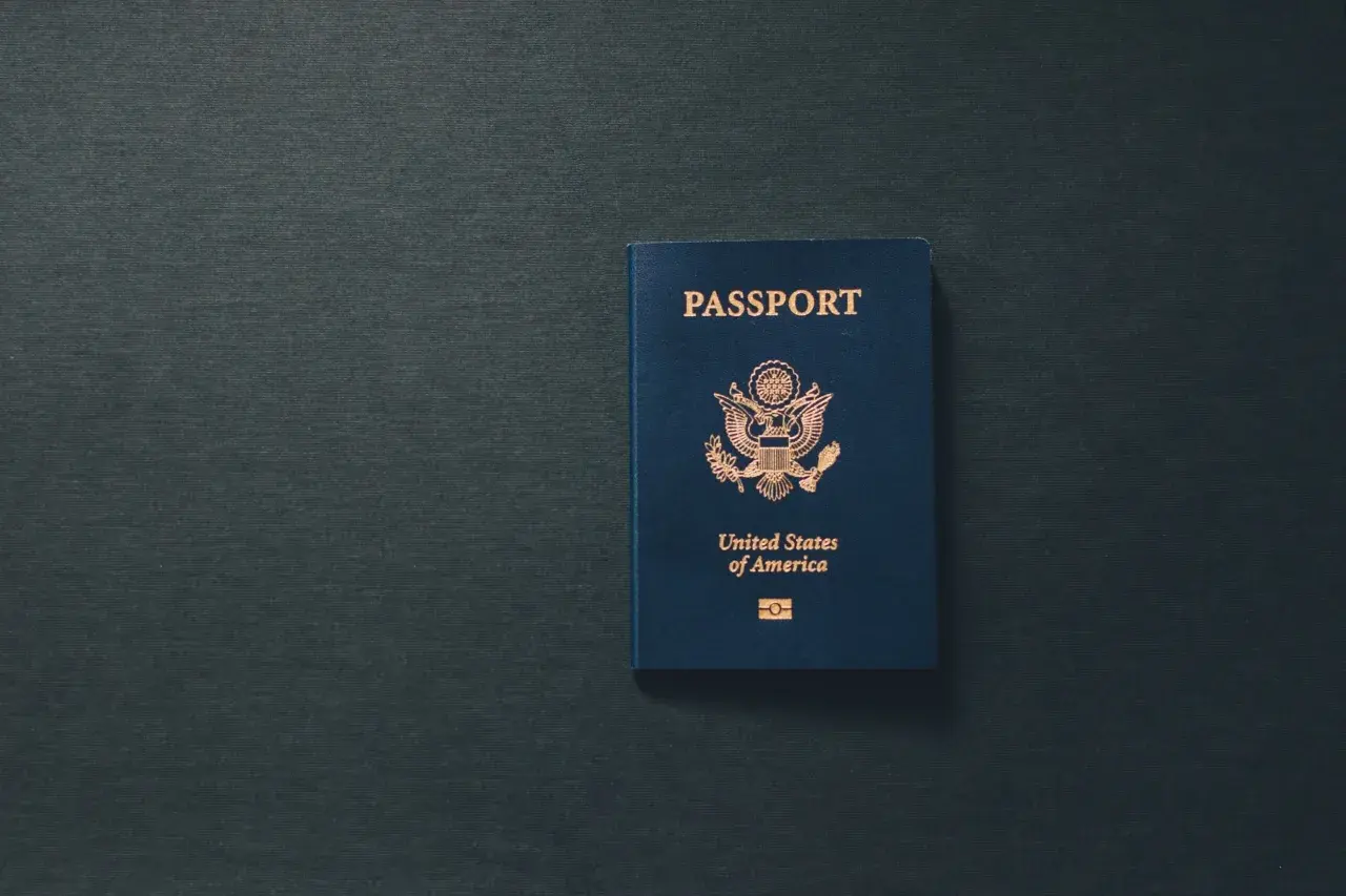 Niebieski paszport USA leży na ciemnym tle. Dokument przypomina o tym, ile ważny jest paszport dla podróżujących.