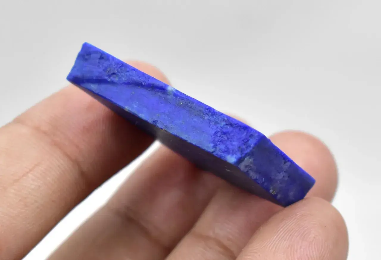 Królewski lapis lazuli, kamień o intensywnym niebieskim kolorze, trzymany w palcach.