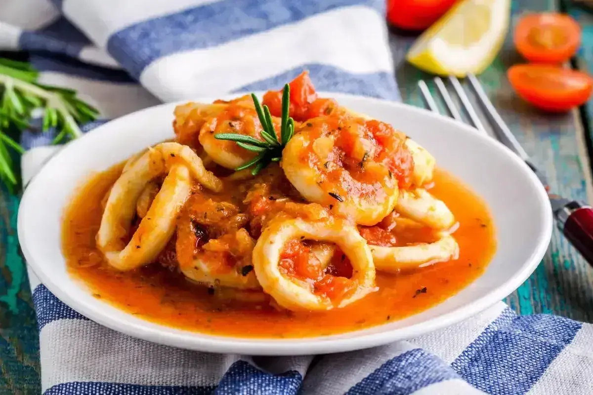 Anelli di calamari in umido con pomodoro e rosmarino, un piatto saporito e invitante.
