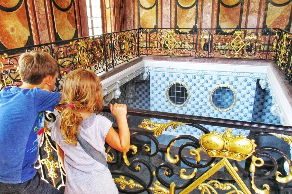 Kinder blicken auf die prunkvolle Treppe im Badenburg Nymphenburg.
