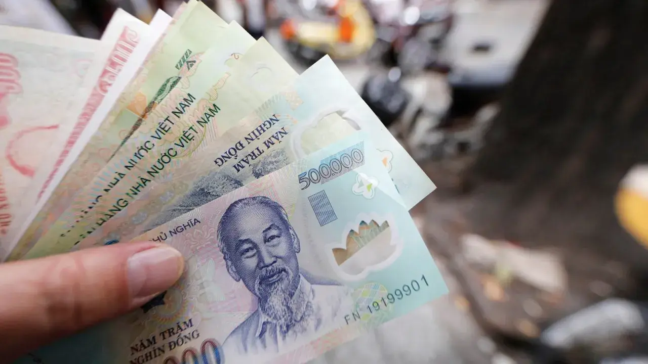 Dłoń trzyma stos banknotów, w tym 500 000 dongów, waluta w Hanoi.