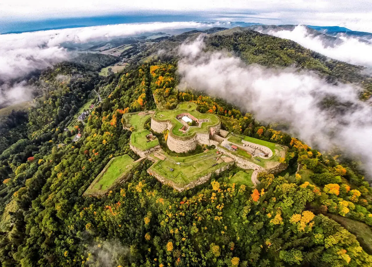 Fortecę na wzgórzu otaczają jesienne lasy. Srebrna Góra oferuje wspaniałe widoki i historyczne atrakcje.