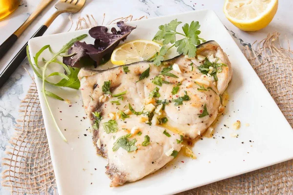 Delicioso emperador a la plancha con ajo, perejil y limón, servido con ensalada.