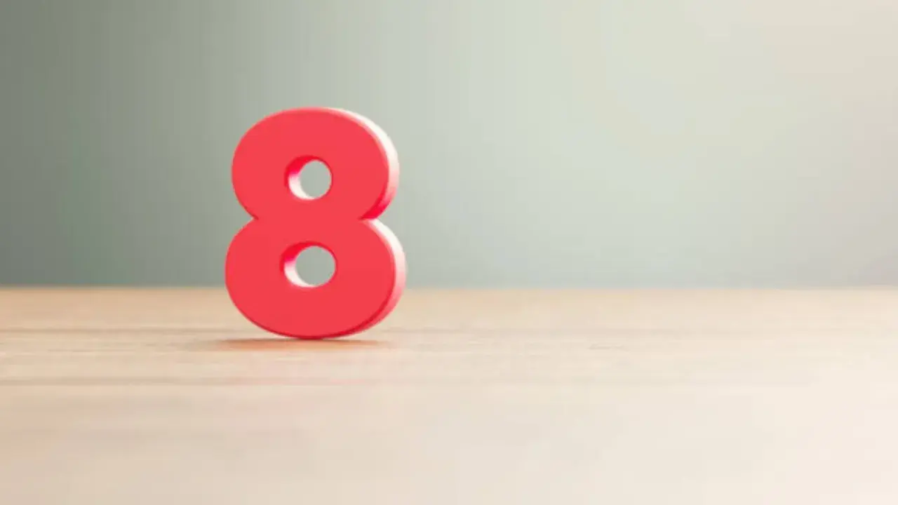Número 8 rojo sobre superficie de madera, simbolizando el significado número 8 en lo espiritual: abundancia, equilibrio y poder infinito.