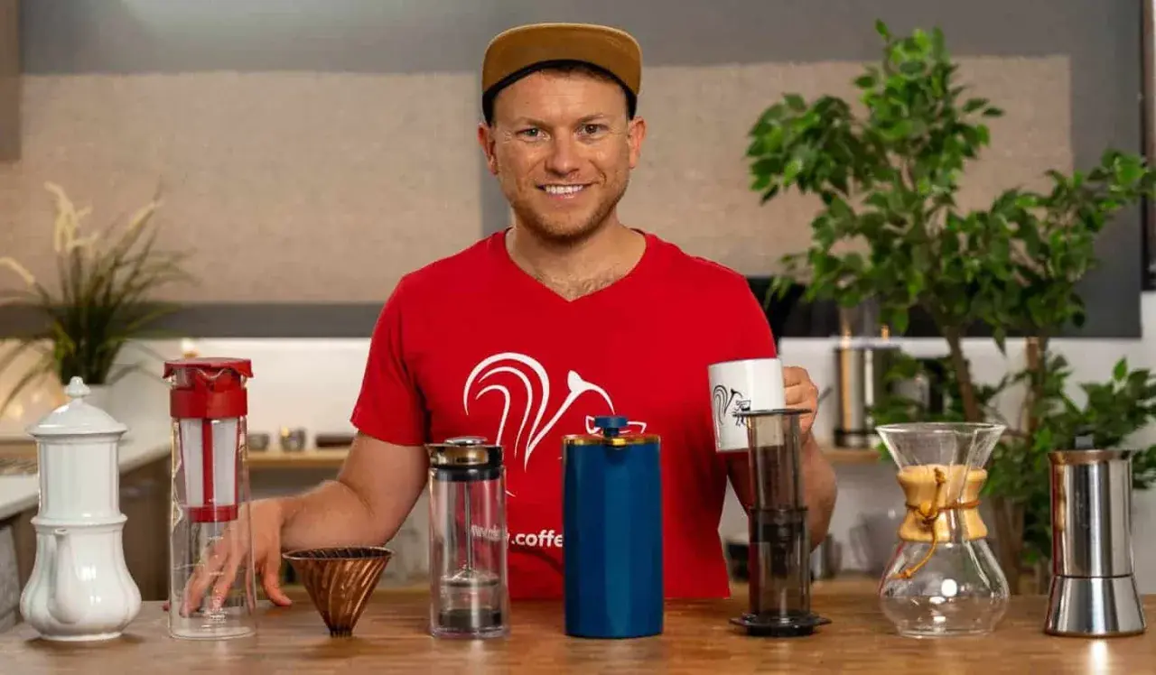 Mann mit verschiedenen Kaffeebereitern, die zeigen, welche Kaffeezubereitung die beste ist.