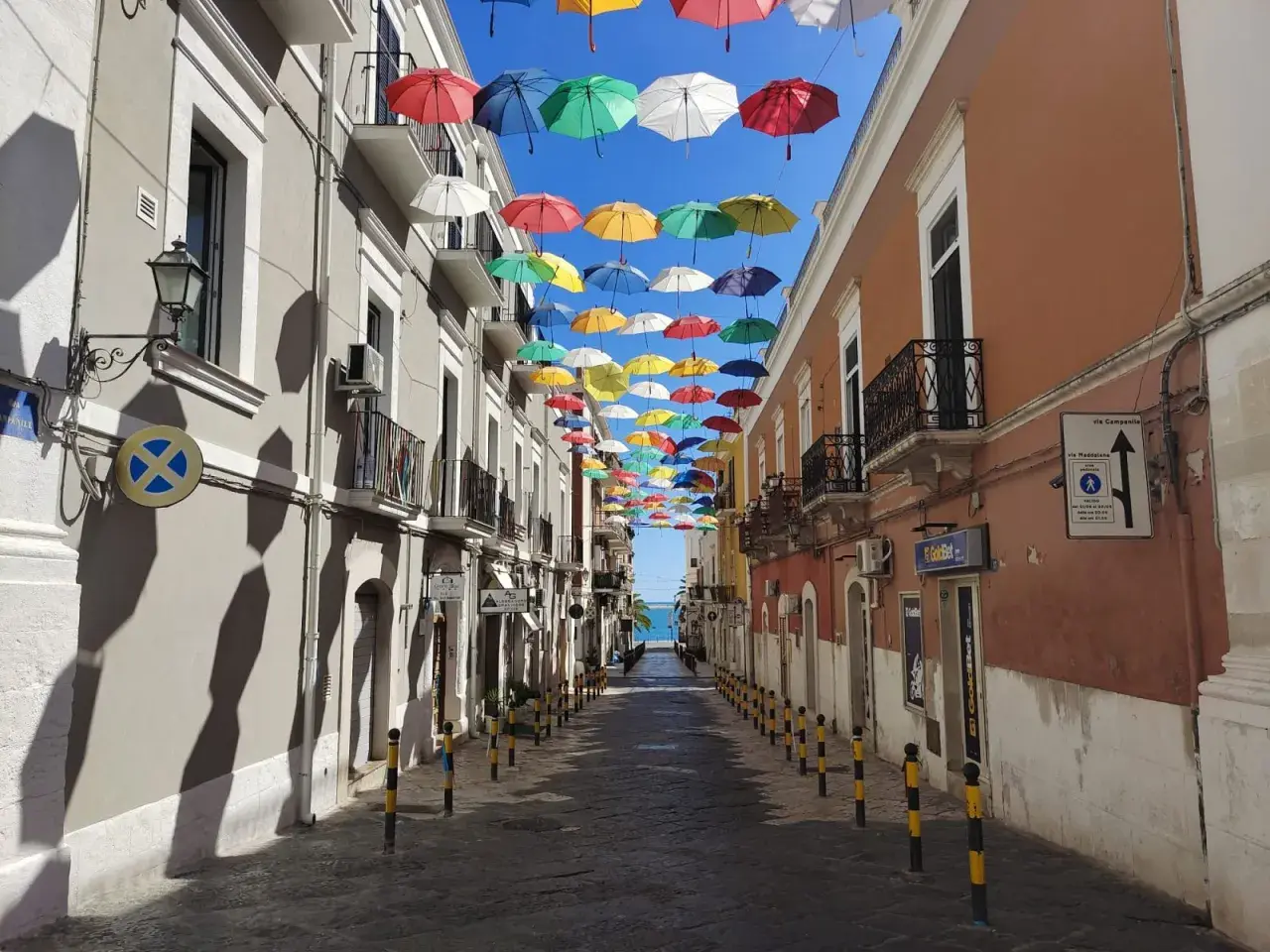 Un vicolo colorato da ombrelli sospesi, un'installazione artistica che rende unica Manfredonia. Ecco cosa vedere a Manfredonia per un'esperienza indimenticabile.