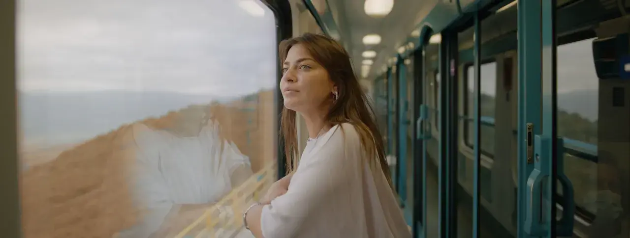En ung kvinna tittar ut genom tågfönstret, drömmande om sin interrail resa.