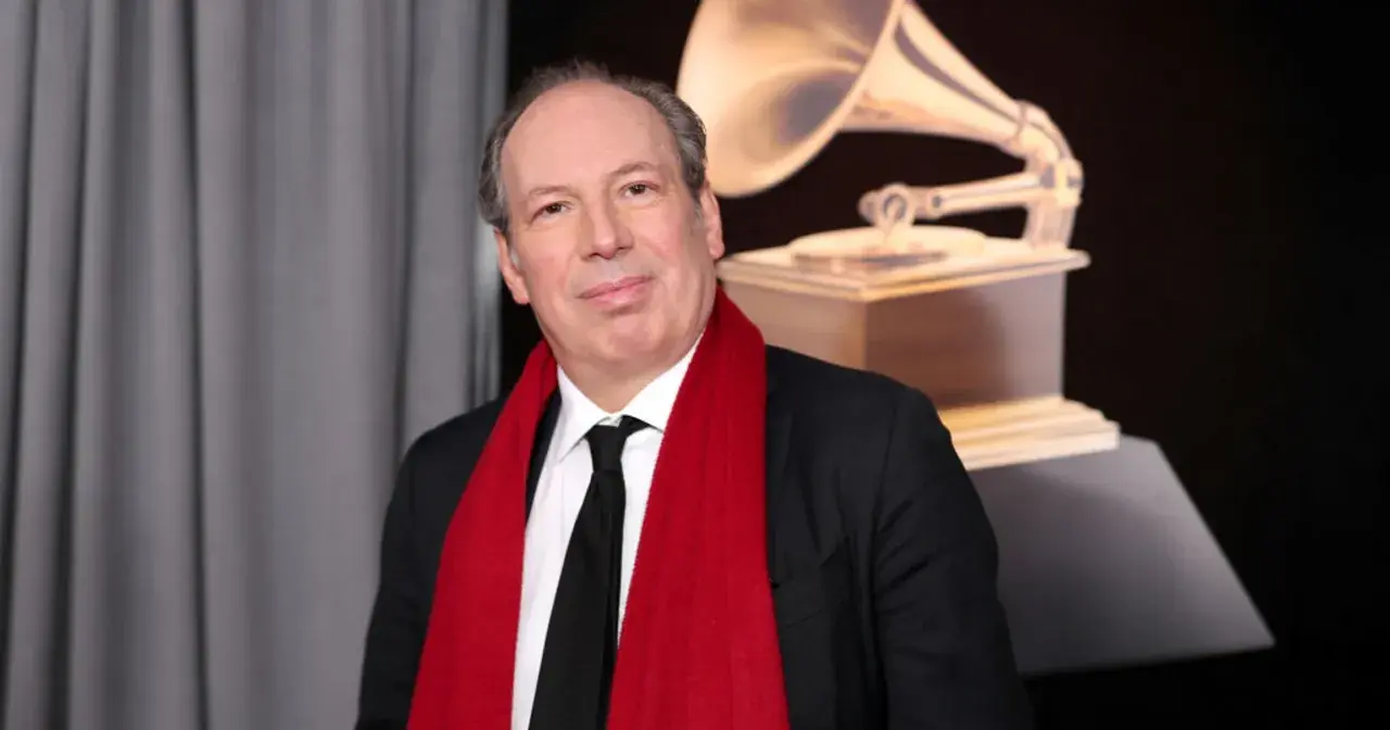 Hans Zimmer, który napisał muzykę do filmu Gladiator, pozuje z czerwoną szarfą i statuetką Grammy.