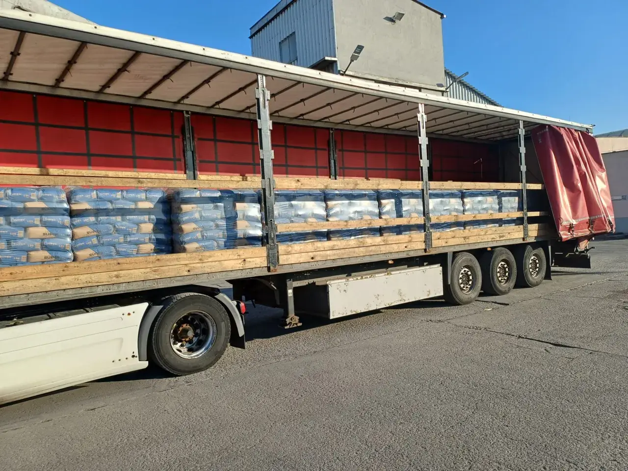Na palecie ciężarówki ułożono worki z cementem. Widać ich sporo, gotowych do transportu.