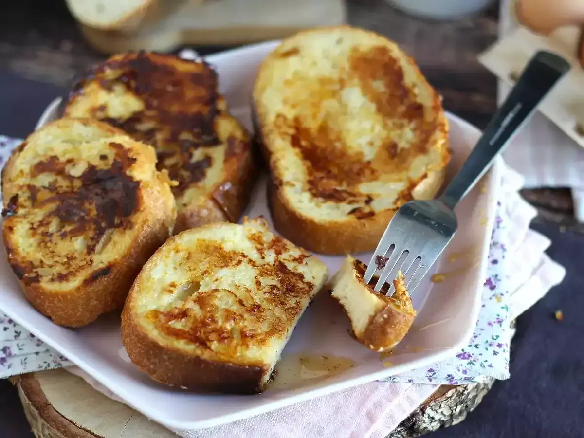 Un plat de pain perdu salé, doré et appétissant, avec une fourchette piquant un morceau. Un délice pour le petit-déjeuner ou le brunch.
