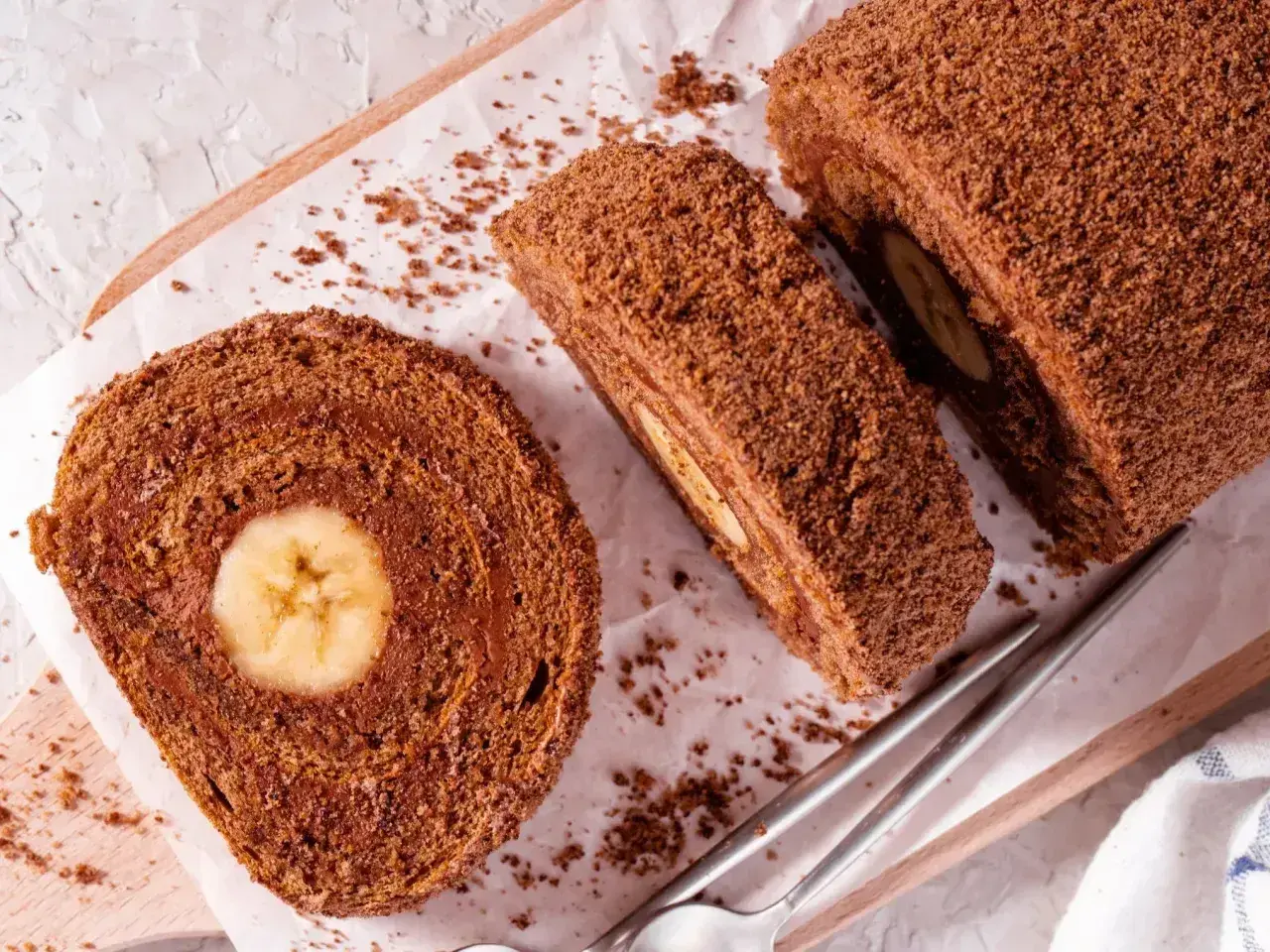 Czekoladowe ciasto gąbka z bananem w środku, pokrojone na plastry, posypane wiórkami.