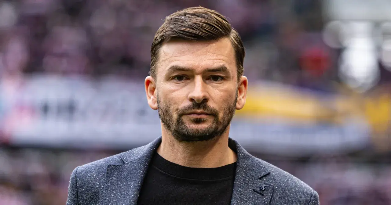 Górnik Zabrze trener, w eleganckim garniturze, patrzy prosto w obiektyw.