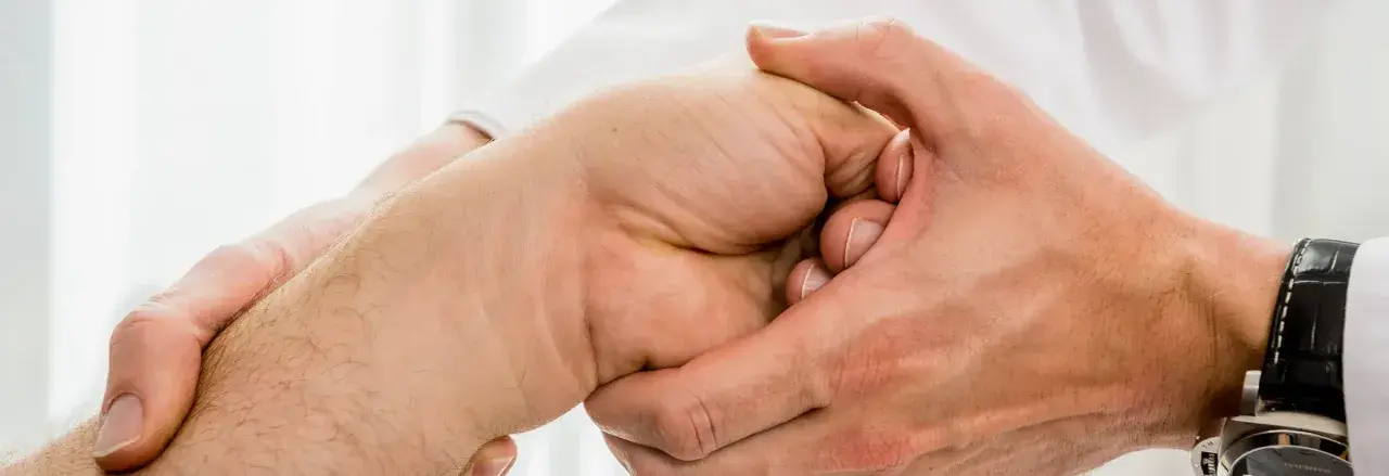 Arzt untersucht Hand, tastet den Os lunatum ab.