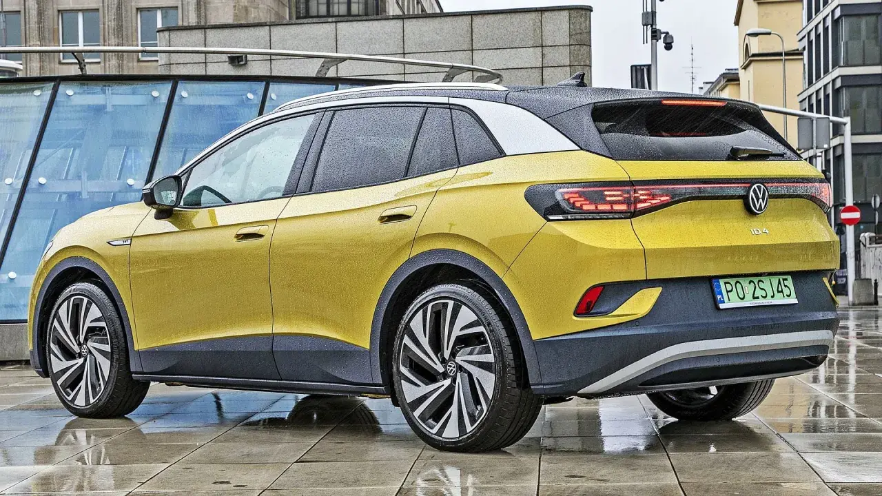 Żółty VW ID.4 z czarnym dachem i felgami stoi na mokrym chodniku.