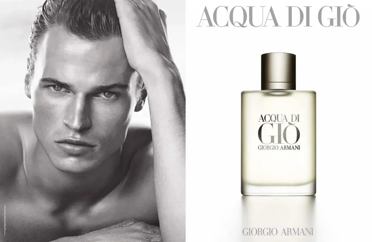 Mężczyzna z dłonią na głowie obok flakonu perfum Acqua di Gio Pour Homme Giorgio Armani.