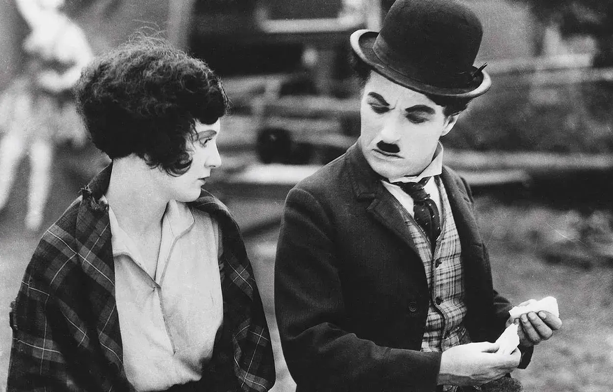 Charlie Chaplin och en kvinna i en klassisk chaplin film. Han ser bekymrad ut medan hon betraktar honom.