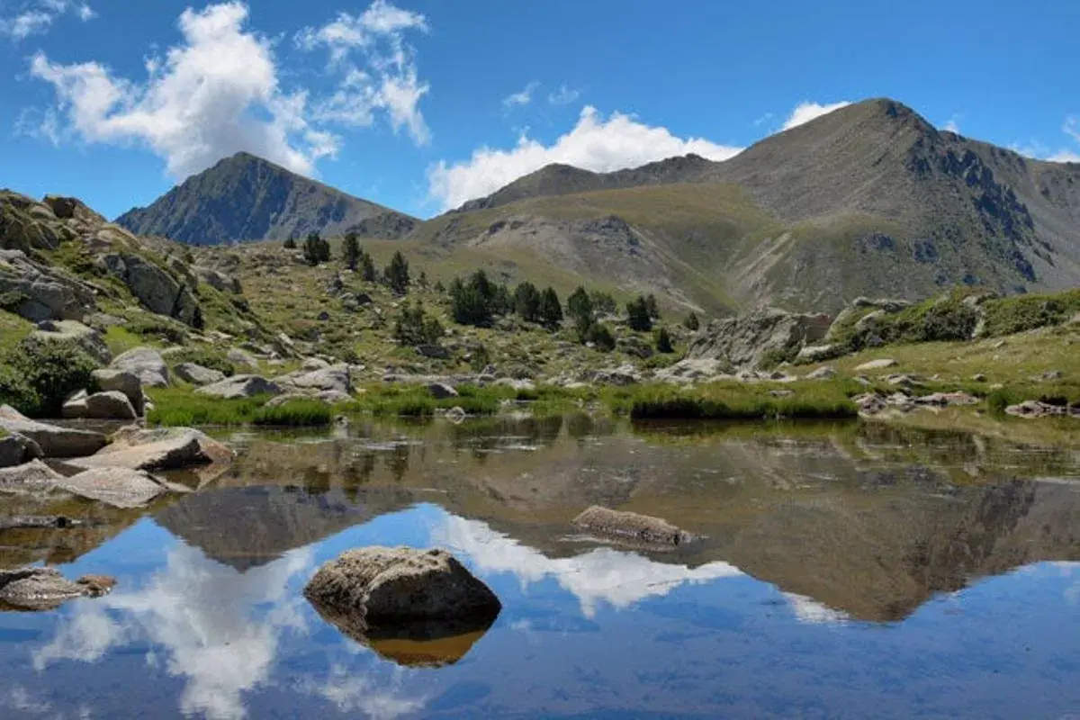 Reflejo de montañas y nubes en un lago sereno del valle de Madriu-Perafita-Claror.