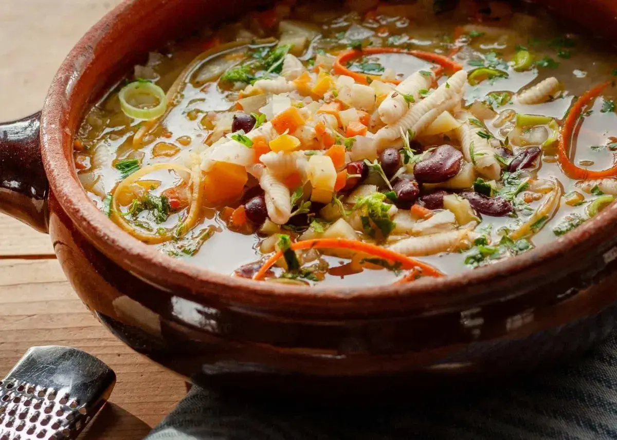 Herzhaftes Minestrone Rezept in einer rustikalen Tonschüssel, gefüllt mit Gemüse, Bohnen und Nudeln.