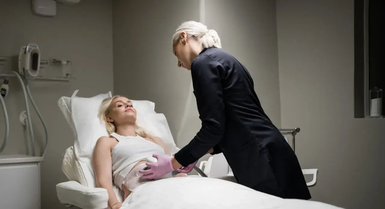 En kvinna får behandling för coolsculpting armar. En terapeut applicerar apparaten på hennes överarm.