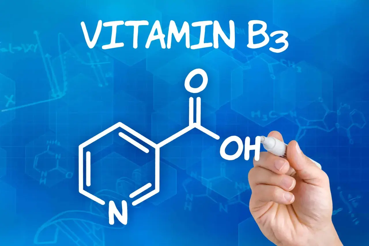 Die chemische Struktur von Vitamin B3, auch bekannt als Niacinamid, wird auf blauem Hintergrund mit Formeln und Graphen gezeichnet.