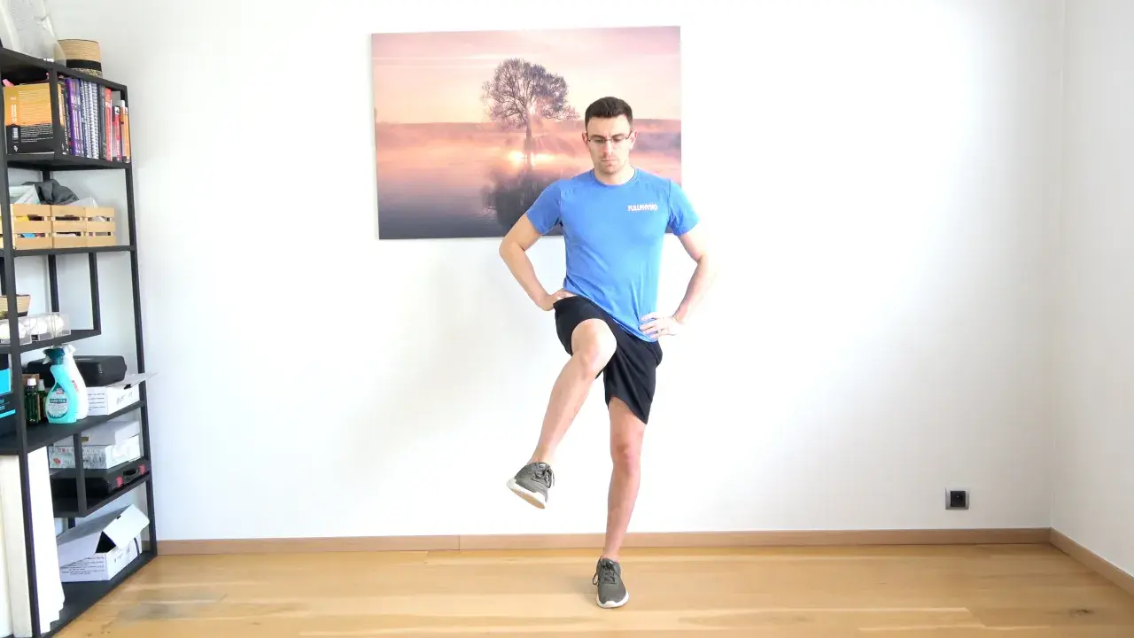 Homme effectuant un exercice de rotation interne hanche, jambe levée, mains sur les hanches.