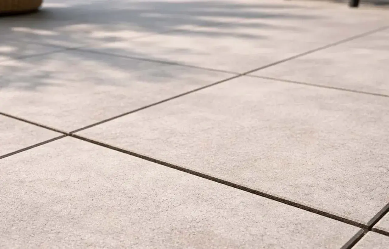 Pavimentazione esterna con piastrelle grigie e fughe scure, perfette per un terrazzo moderno. Il cemento per fughe esterne garantisce durata e stile.