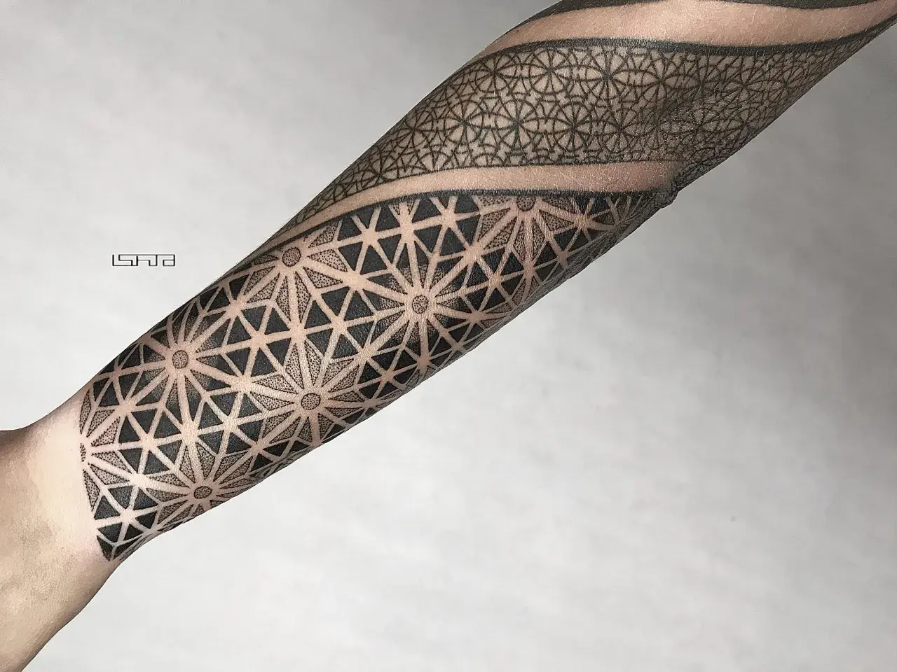 Geometryczny tatuaż dotwork na przedramieniu, tworzący hipnotyzujący wzór z trójkątów i kropek.